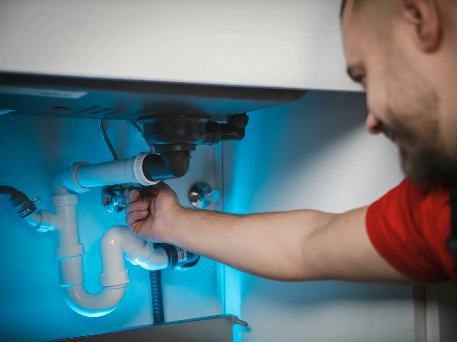 Plomero reparando la tubería de un lavabo